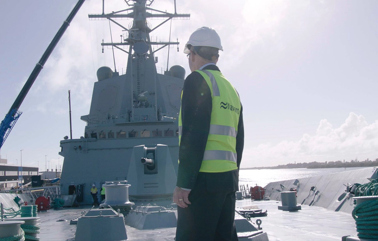 Worker standing in front of a frigate, with the ship visible in the background