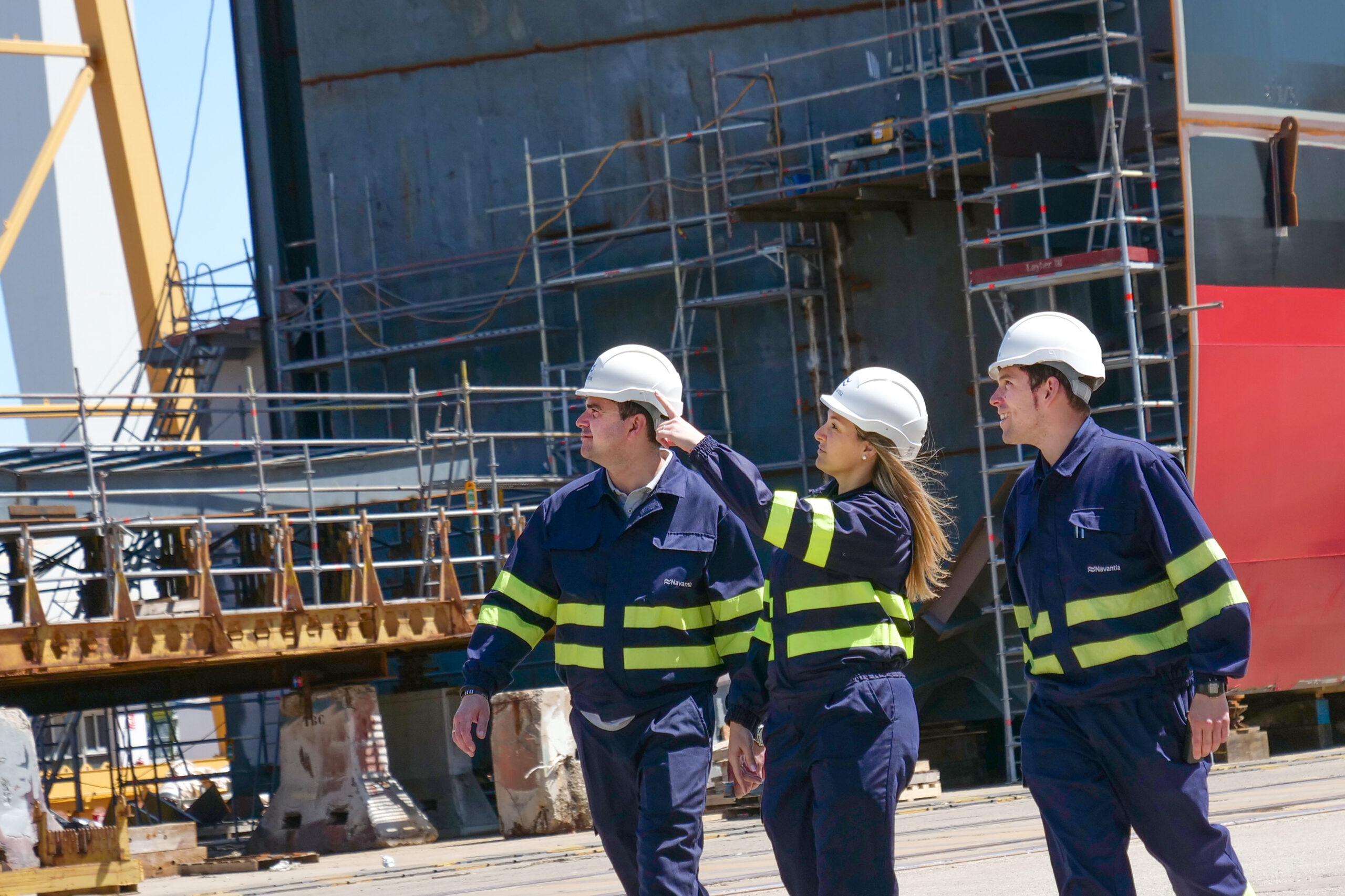 Three workers on a construction site, supervising ongoing construction activities and reviewing progress